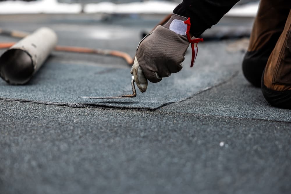 Roofer sealing a felt roof seam