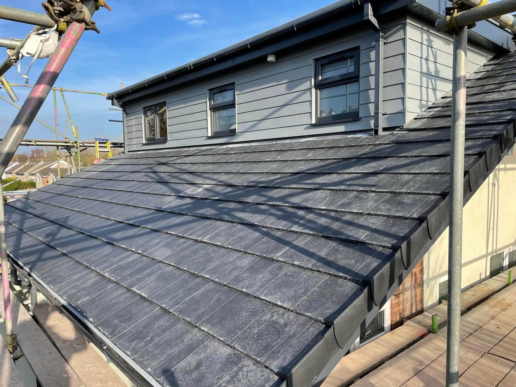 Slate roof and grey-clad dormer surrounded by scaffolding