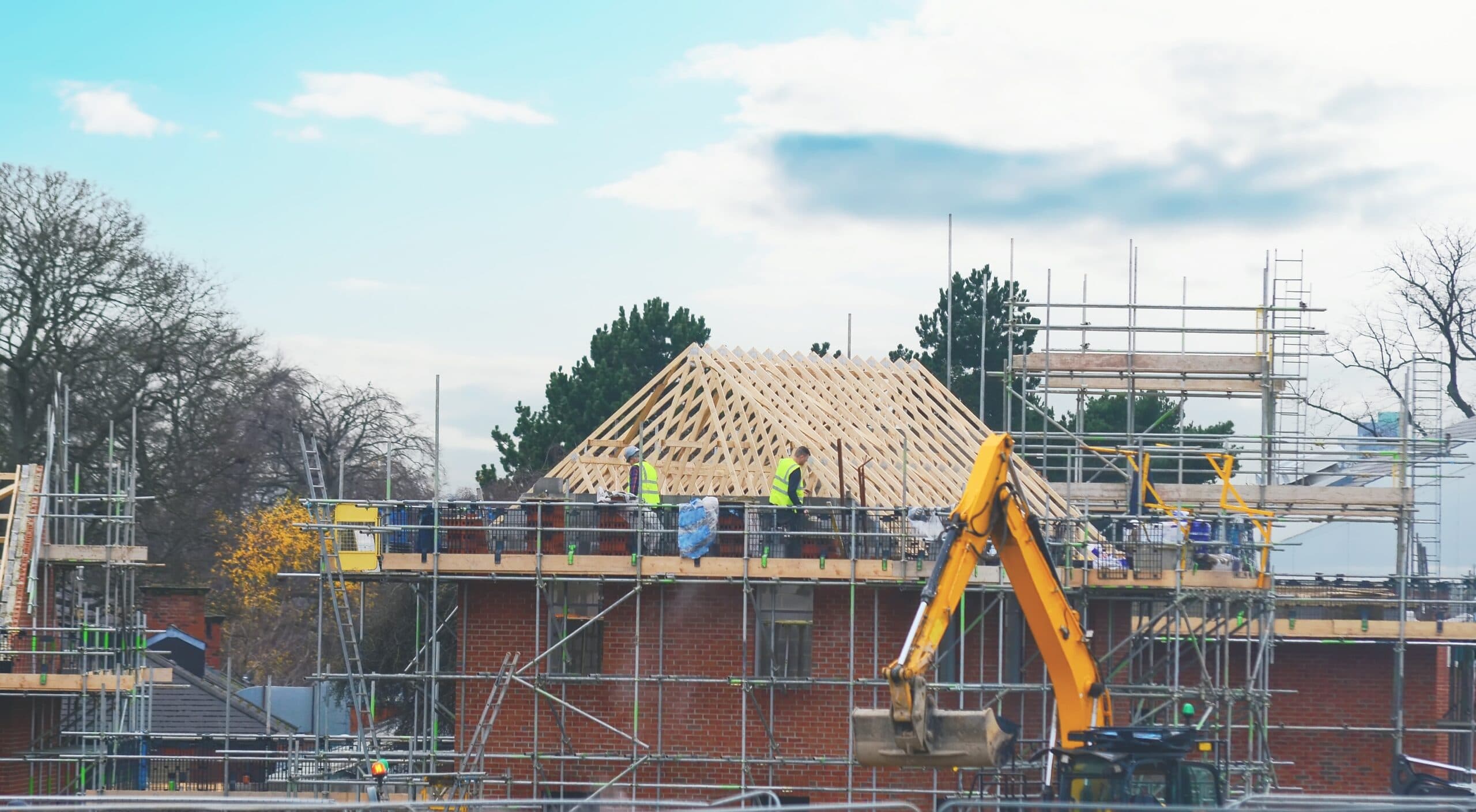Roofers working on a timber roof structure with scaffolding