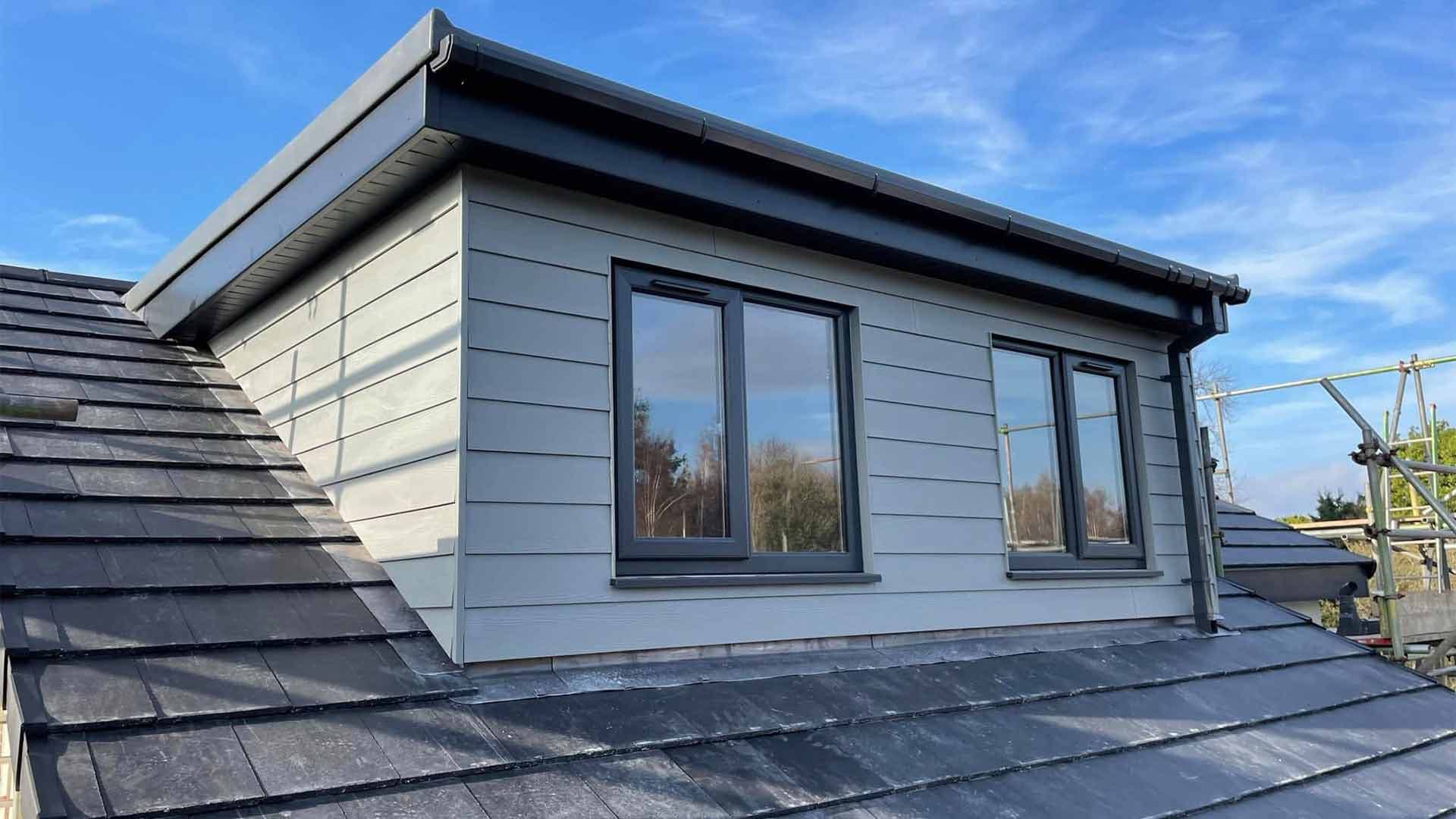 Grey-clad dormer with two windows and slate roof detailing