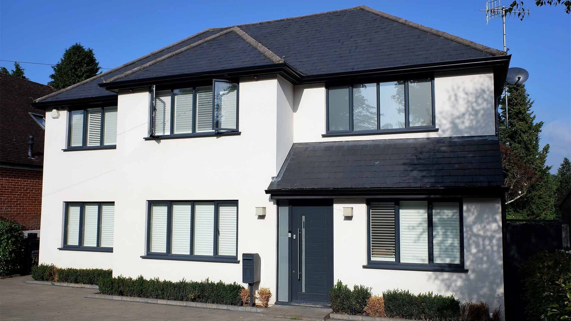 White house with a dark slate hipped roof and matching porch roof