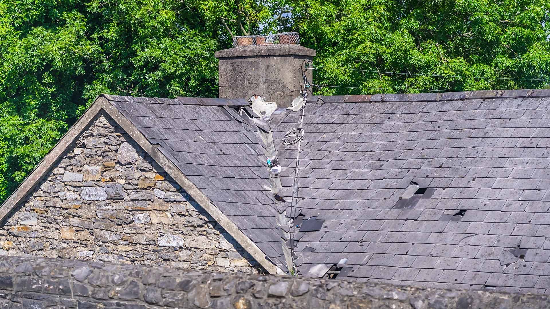 Slate roof with missing tiles and a chimney requiring repair